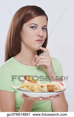 Woman holding a plate of hot dog and thinking View Large Photo Image Stock Image - Woman holding a plate of hot dog and thinking. Fotosearch