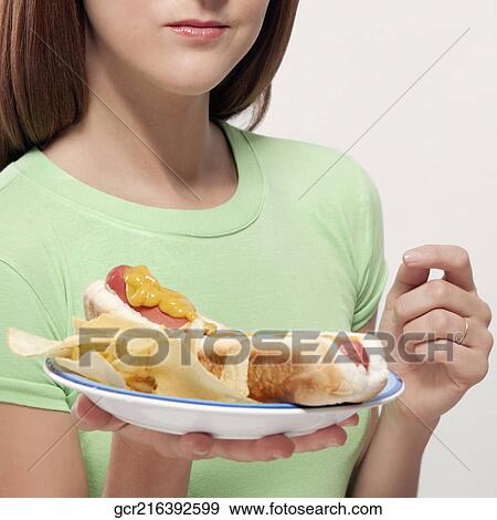 Woman holding a plate of hot dog and potato chips View Large Photo Image Stock Photo - Woman holding a plate of hot dog and potato chips. Fotosearch