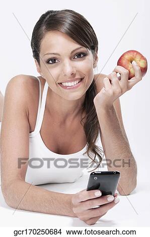 Woman holding a red apple and using a mobile phone View Large Photo Image Picture - Woman holding a red apple and using a mobile phone. Fotosearch