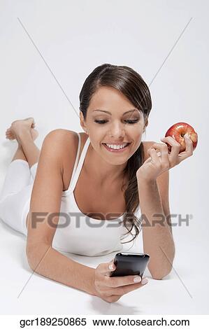 Woman holding a red apple and using a mobile phone View Large Photo Image Stock Photography - Woman holding a red apple and using a mobile phone. Fotosearch