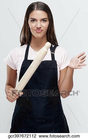 Stock Image - Woman holding a rolling pin and frowning. Fotosearch