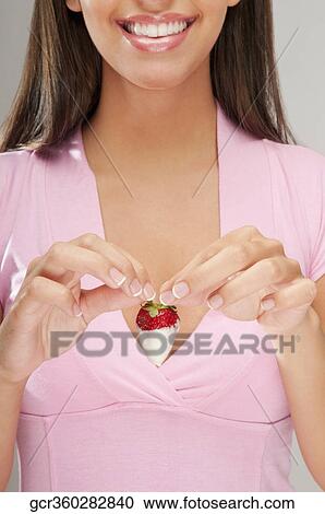 Woman holding a strawberry dipped in cream and smiling View Large Photo Image Stock Image - Woman holding a strawberry dipped in cream and smiling. Fotosearch