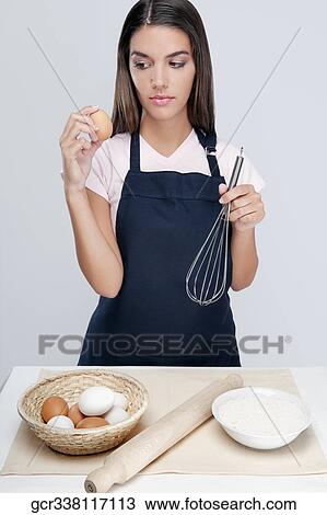 Woman holding an egg and wire whisk and thinking View Large Photo Image Stock Image - Woman holding an egg and wire whisk and thinking. Fotosearch