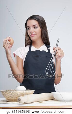 Woman holding an egg and wire whisk View Large Photo Image Stock Image - Woman holding an egg and wire whisk. Fotosearch