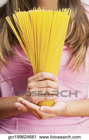 Woman holding uncooked spaghetti View Large Photo Image Stock Image - Woman holding uncooked spaghetti. Fotosearch
