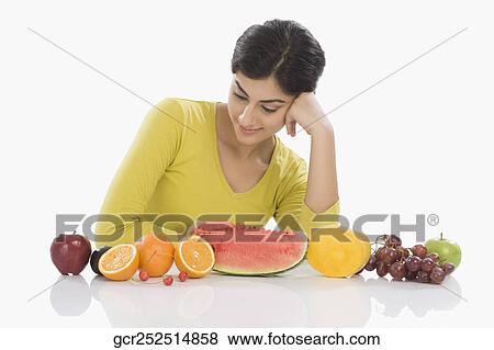 Stock Photo - Woman looking at a row of assorted fresh fruits. Fotosearch