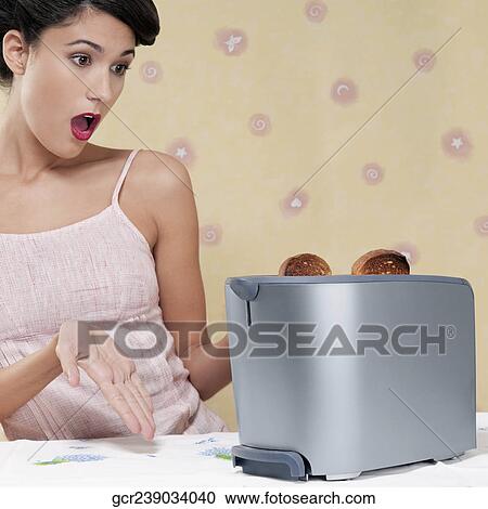 Woman looking at a toaster with a surprise View Large Photo Image Stock Image - Woman looking at a toaster with a surprise. Fotosearch