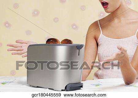 Stock Photo - Woman looking surprised in the kitchen. Fotosearch