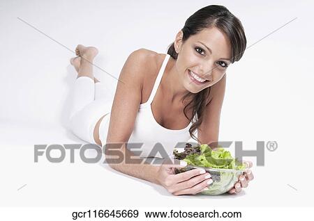 Woman lying with a bowl of salad in her hands View Large Photo Image Stock Photo - Woman lying with a bowl of salad in her hands. Fotosearch