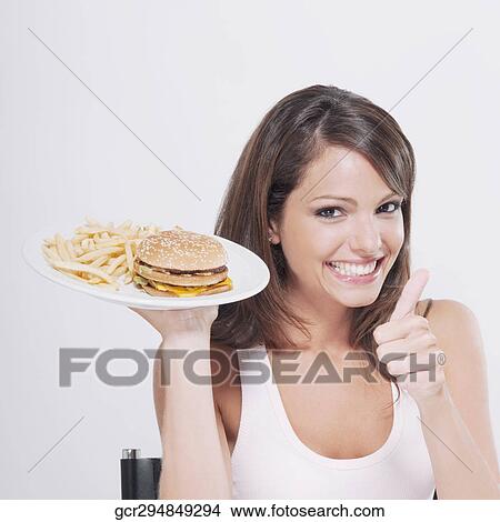 Woman making a thumbs up sign with a plate of hamburger and fries View Large Photo Image Picture - Woman making a thumbs up sign with a plate of hamburger and fries . Fotosearch