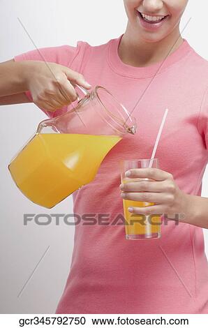 Woman pouring orange juice from a jug View Large Photo Image Stock Image - Woman pouring orange juice from a jug. Fotosearch