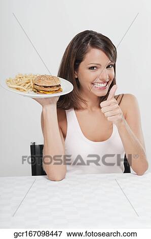 Stock Photo - Woman showing a Thumbs Up sign with a plate of burger and French fries. Fotosearch