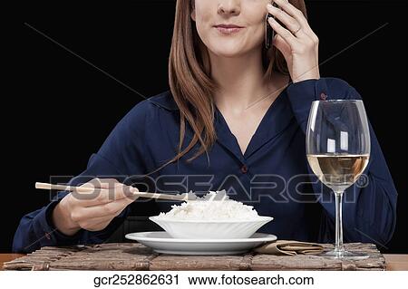 Woman talking on a mobile phone and eating rice View Large Photo Image Stock Image - Woman talking on a mobile phone and eating rice. Fotosearch