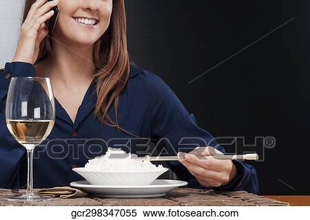Woman talking on a mobile phone and eating rice View Large Photo Image Stock Photography - Woman talking on a mobile phone and eating rice. Fotosearch