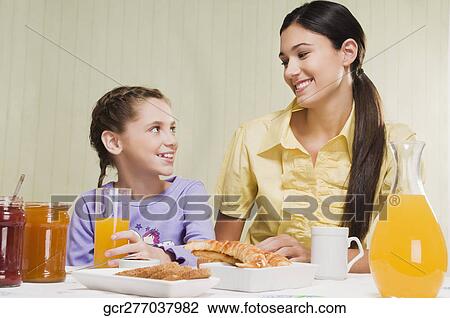 Woman with her daughter at a breakfast table View Large Photo Image Stock Image - Woman with her daughter at a breakfast table. Fotosearch