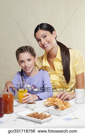 Woman with her daughter at a breakfast table View Large Photo Image Stock Photograph - Woman with her daughter at a breakfast table. Fotosearch