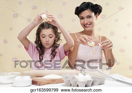 Woman with her daughter breaking eggs View Large Photo Image Stock Photo - Woman with her daughter breaking eggs. Fotosearch