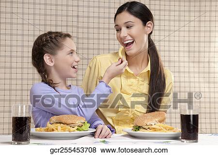 Stock Photo - Woman with her daughter having breakfast. Fotosearch