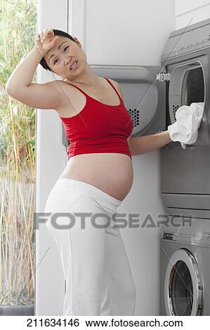 Stock Photograph - Annoyed pregnant woman washing clothes. Fotosearch