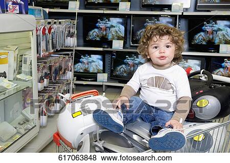 Baby boy sitting on a shopping cart in a supermarket View Large Photo Image Stock Photo - Baby boy sitting on a shopping cart in a supermarket. Fotosearch