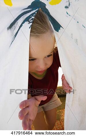 Picture - Baby girl peeking out from a tent. Fotosearch