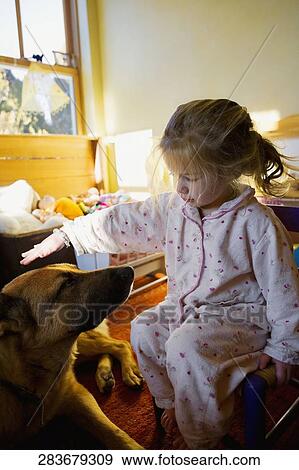 Stock Photo - Baby girl playing with a dog. Fotosearch