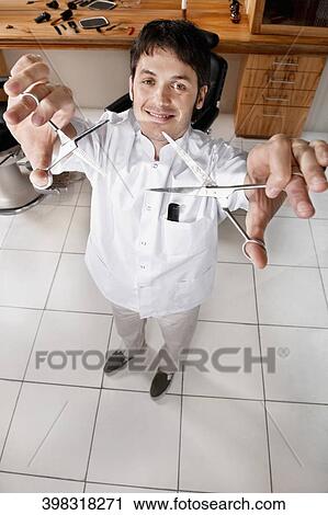 Stock Image - Barber holding scissors in a salon. Fotosearch