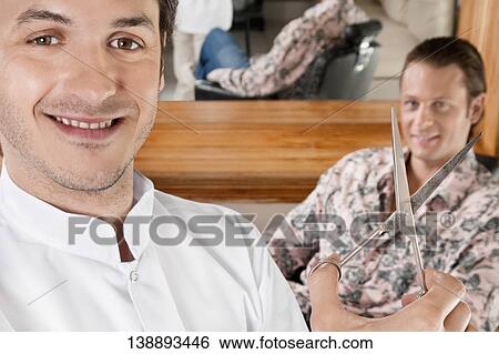 Barber holding scissors with a man in the background View Large Photo Image Stock Photograph - Barber holding scissors with a man in the background. Fotosearch