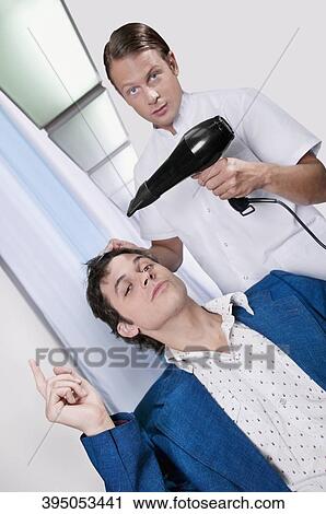 Barber using a hair dryer on a man's hair View Large Photo Image Stock Image - Barber using a hair dryer on a man's hair. Fotosearch