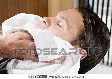 Barber wiping a man's face with a towel View Large Photo Image Stock Photo - Barber wiping a man's face with a towel. Fotosearch