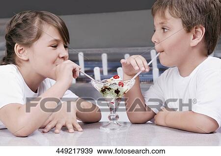 Boy and a girl sharing ice cream in an ice cream parlor View Large Photo Image Stock Photo - Boy and a girl sharing ice cream in an ice cream parlor. Fotosearch