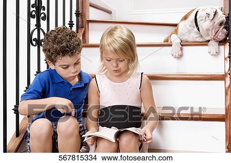 Boy and a girl sitting on a staircase and reading a book View Large Photo Image Picture - Boy and a girl sitting on a staircase and reading a book. Fotosearch