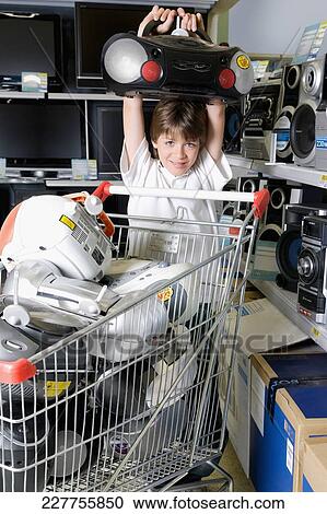 Stock Image - Boy carrying a stereo in a supermarket. Fotosearch