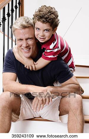 Boy hugging his father on a staircase View Large Photo Image Stock Photo - Boy hugging his father on a staircase. Fotosearch