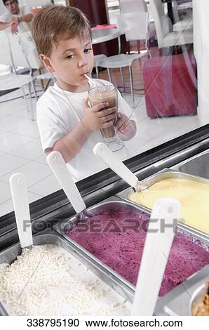 Boy looking at ice creams while drinking milkshake View Large Photo Image Stock Image - Boy looking at ice creams while drinking milkshake. Fotosearch