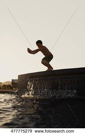 Stock Photo - Boy preparing to jump into a swimming pool. Fotosearch