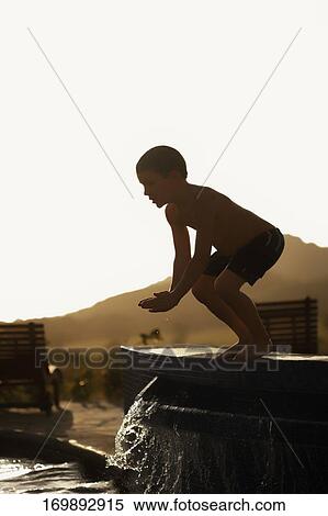 Boy preparing to jump into a swimming pool View Large Photo Image Stock Photography - Boy preparing to jump into a swimming pool. Fotosearch