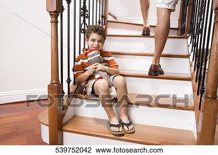 Boy sitting on a staircase and holding a toy View Large Photo Image Stock Image - Boy sitting on a staircase and holding a toy. Fotosearch
