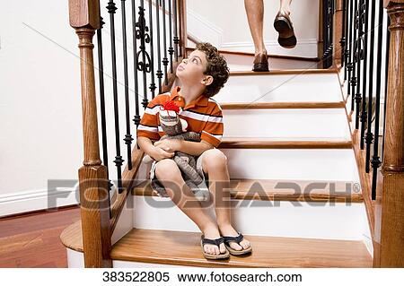 Boy sitting on a staircase and holding a toy View Large Photo Image Stock Photography - Boy sitting on a staircase and holding a toy. Fotosearch
