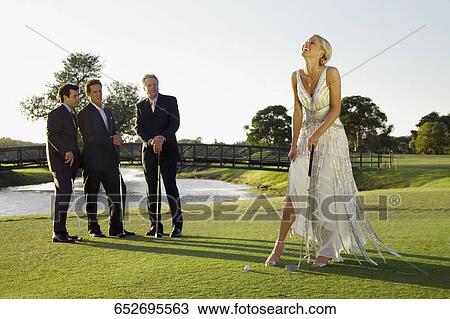 Stock Image - Bride playing golf and three men watching her, Biltmore Golf Course, Coral Gables, Florida, USA. Fotosearch