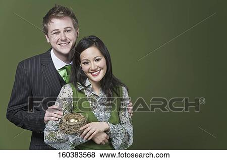 Business couple holding a golden egg in the nest View Large Photo Image Stock Photo - Business couple holding a golden egg in the nest. Fotosearch