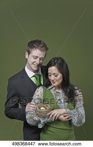 Business couple holding a golden egg in the nest View Large Photo Image Stock Photo - Business couple holding a golden egg in the nest. Fotosearch