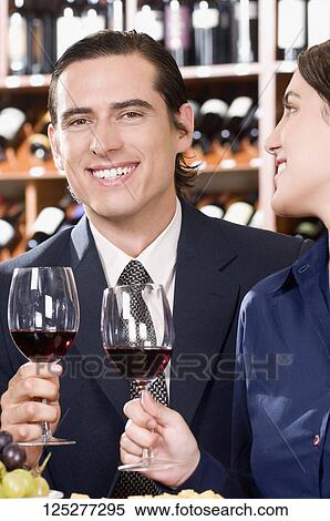 Business couple holding wine glasses and smiling View Large Photo Image Stock Photography - Business couple holding wine glasses and smiling. Fotosearch