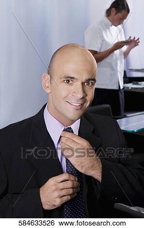 Stock Photograph - Businessman adjusting his tie in a salon. Fotosearch