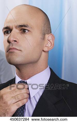 Businessman adjusting his tie View Large Photo Image Picture - Businessman adjusting his tie. Fotosearch