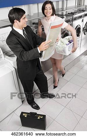 Businessman and a woman reading a newspaper in a laundromat View Large Photo Image Stock Image - Businessman and a woman reading a newspaper in a laundromat. Fotosearch