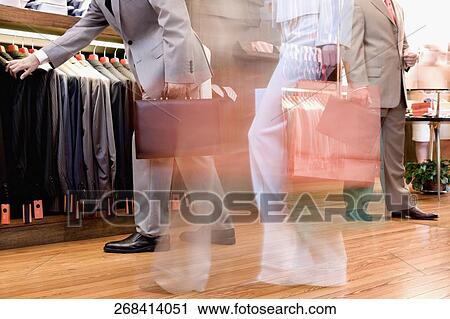 Businessman and a woman shopping in a clothing store View Large Photo Image Stock Image - Businessman and a woman shopping in a clothing store. Fotosearch