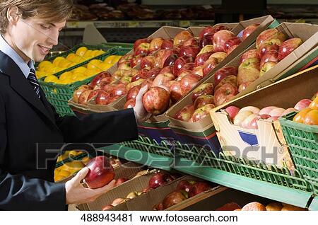 Stock Image - Businessman buying apples in a supermarket. Fotosearch