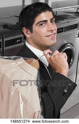Businessman carrying a hanger in a laundromat View Large Photo Image Picture - Businessman carrying a hanger in a laundromat. Fotosearch