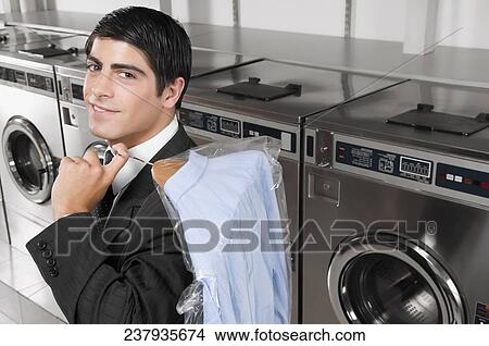 Businessman carrying a hanger in a laundromat View Large Photo Image Picture - Businessman carrying a hanger in a laundromat. Fotosearch